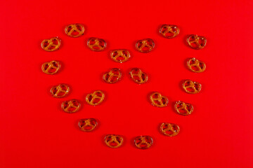 Mini pretzels in the shape of knot lie on vibrant red background. Pretzel Sunday concept