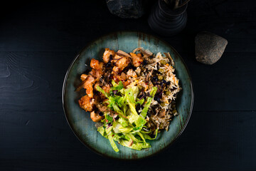 Fried pieces of chicken fillet with rice, mushrooms, greens and spices.