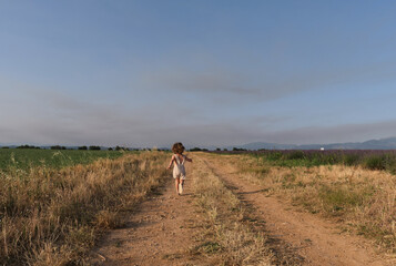 little girl enjoying the freedom of running along a path in the middle of the field.