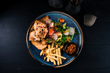 Chicken fillet with French fries, fresh vegetable salad and sauce.