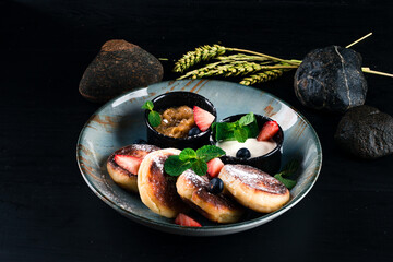 Fresh cheese pancakes with jam, sour cream, blueberries, strawberries, mint and powdered sugar.