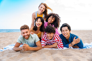 Multiethnic group of happy friends bonding and having fun at the beach on summer vacation - Multiracial real authentic people spending time together at the sea, concepts about youth and summertime