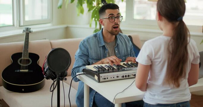 little awesome talented kid singing a song to the piano. The music teacher and the student are parsing a new song, giving a vocal lesson.vocal exercises, warm up beore perormance, concert slow motion