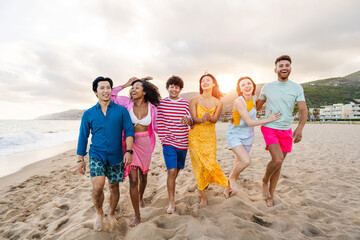 Multiethnic group of happy friends bonding and having fun at the beach on summer vacation - Multiracial real authentic people spending time together at the sea, concepts about youth and summertime