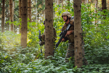 Naklejka na ściany i meble A group of modern warfare soldiers is fighting a war in dangerous remote forest areas. A group of soldiers is fighting on the enemy line with modern weapons. The concept of warfare and military