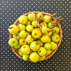 high angle view of fresh green apples in basket on polka dot tablecloth
