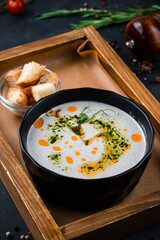 Champignon cream soup in a bowl served with green peas and oil.