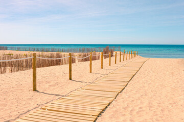 Access to the beach, walkway to the beach with wooden walkway on a sunny day with golden sand
