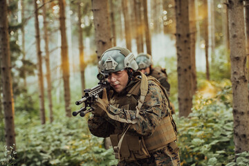A group of modern warfare soldiers is fighting a war in dangerous remote forest areas. A group of soldiers is fighting on the enemy line with modern weapons. The concept of warfare and military