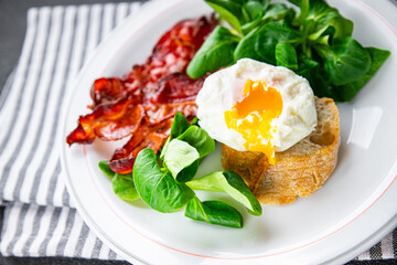 egg poached fesh breakfast bacon, green leaves salad healthy meal food snack on the table copy space food background rustic top view