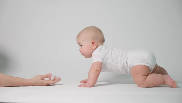 Baby 6 months old learning to crawl with parental help, the concept of child development and health