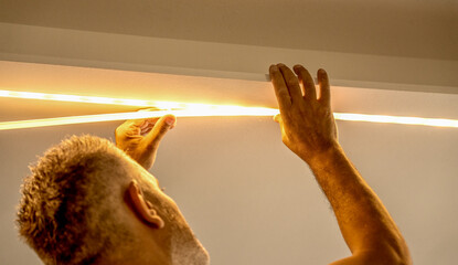 Led strip with yellow warm light, light installation. Male installer