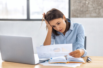Upset businesswoman behind paper work office, reading bad financial reports and account documents....