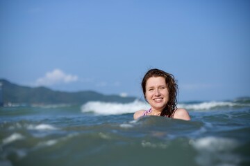 Portrait of happy positive girl, young woman swimming in sea or ocean, enjoying summer vacation, smile, laugh, have fun in water 