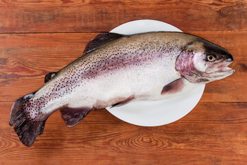 Fresh rainbow trout on big white dish on rustic table