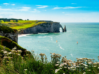 Dreamlike view of Etretat coastline, green fields and vertical chalk cliffs with characteristic...