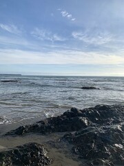 Fototapeta na wymiar waves on the beach with rocks and blue sky