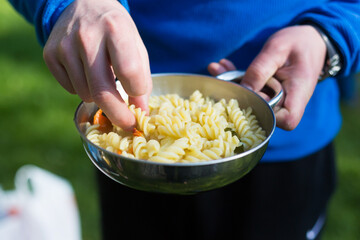 hands holding a bowl of pasta