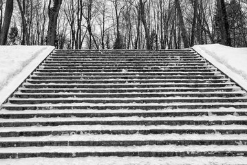 High staircase in the park with steps littered with snow. Rise up. Winter walk in the park.