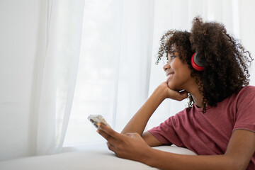 Young African woman sitting and listening the music. Portrait of happy woman listening music with earphones while singing song.
