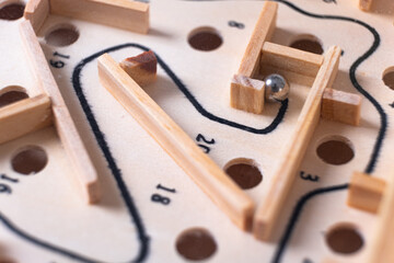 Wooden labyrinth toy marble maze game. Ball bearing navigating a vintage traditional wooden maze, close up, macro shot