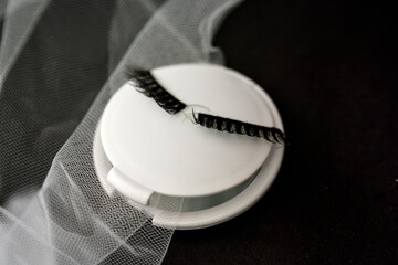A small mirror with eyelashes, on a black background with tulle around
