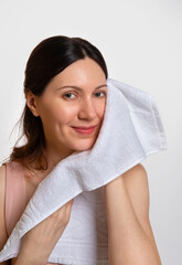Washing face. Closeup of woman with towel. Beautiful woman wiping facial skin with soft facial towel