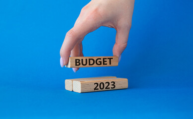 Budget 2023 symbol. Wooden blocks with words Budget 2023. Beautiful blue background. Businessman hand. Business and Budget 2023 concept. Copy space.