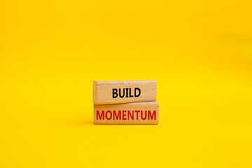 Build momentum symbol. Wooden blocks with words Build momentum. Beautiful yellow background. Business and Build momentum concept. Copy space.