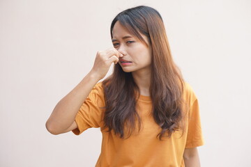 Asian woman covering her nose with her hands due to smell