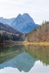 Fototapeta na wymiar View over the Riessersee, Riessersee in the Ammergau Alps to the south to the Zugspitze in autumn. In the cold clear air the mountain panorama is well visible. The mixed forest is colored in autumn.