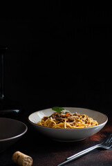 Traditional Italian pasta spaghetti bolognese served on a dark table with a black background....