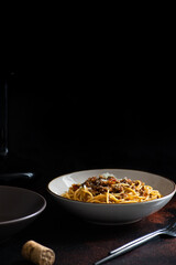 Traditional Italian pasta spaghetti bolognese served on a dark table with a black background. Classic meal of global world cuisine