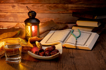 Many Date Palms are on bowls, plates, a cup of water, and Quran, an Islami-style lamp on the wooden tables, to wait for the time of Iftar, with the concept of fruits from Muslims around the world.