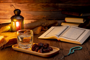 Many Date Palms are on bowls, plates, a cup of water, and Quran, an Islami-style lamp on the wooden tables, to wait for the time of Iftar, with the concept of fruits from Muslims around the world.