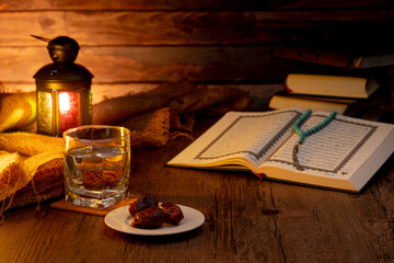 Many Date Palms are on bowls, plates, a cup of water, and Quran, an Islami-style lamp on the wooden tables, to wait for the time of Iftar, with the concept of fruits from Muslims around the world.