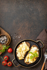 Scrambled eggs on whole grain bread. Homemade breakfast or brunch meal - scrambled eggs. View from above. Copy space.