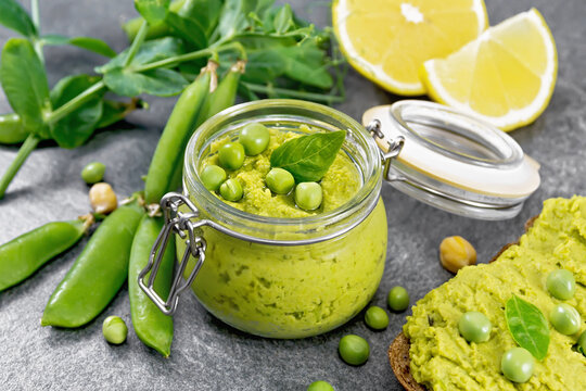 Hummus from green peas in glass jar on granite table