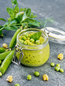 Hummus from green peas in jar on stone table