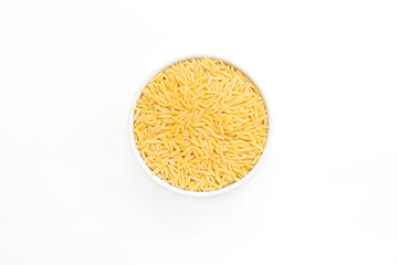 Risoni or orzo rice shaped pasta in white ceramic bowl on white background. Italian cuisine. Durum wheat semolina pasta for risotto and salads. Closeup, horizontal plane, top view, flatly