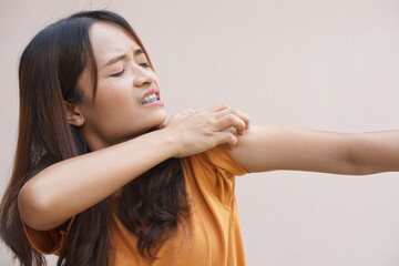 Asian woman having an itchy shoulder