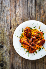 Barbecue chicken drumsticks with French fries on wooden table
