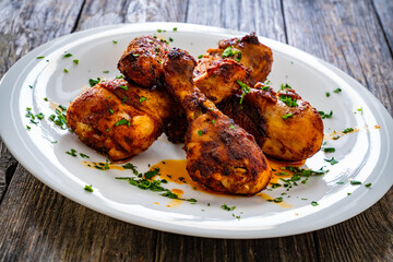 Barbecue chicken drumsticks with French fries on wooden table
