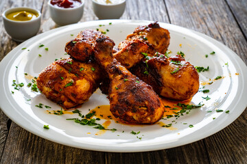 Barbecue chicken drumsticks with French fries on wooden table
