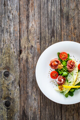 Tasty salad - prosciutto crudo, melon and fresh vegetables on wooden table
