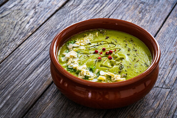 Cream green peas soup on wooden table
