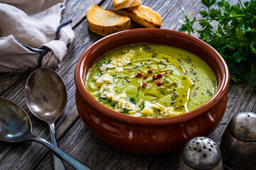 Cream green peas soup on wooden table
