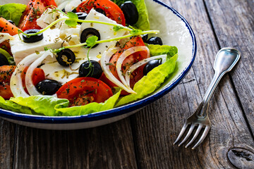 Fresh vegetable salad with feta cheese on wooden table
