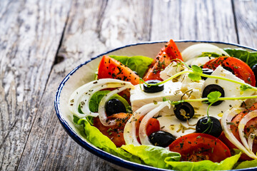 Fresh vegetable salad with feta cheese on wooden table
