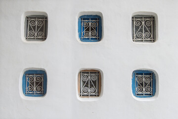 six small windows with bars on a white wall